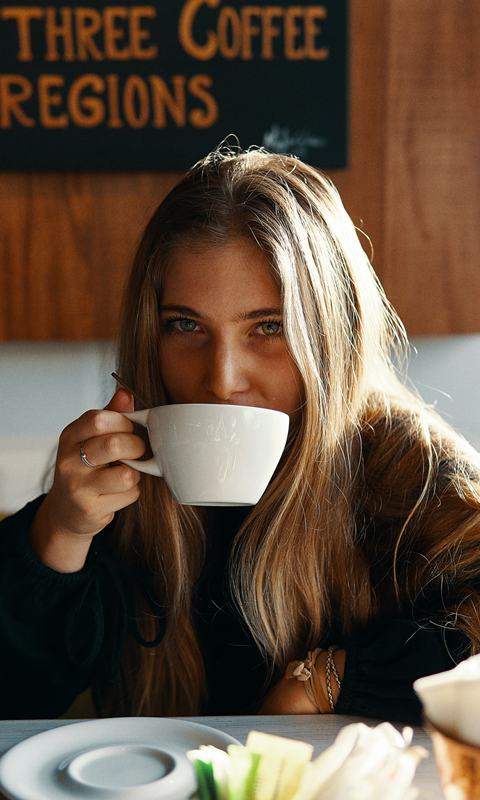 Woman drinking a cup of coffee from a white mug.